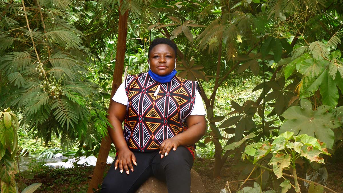 Ecologist Limbi Blessing Tata sitting on a rock, surrounded by forest.