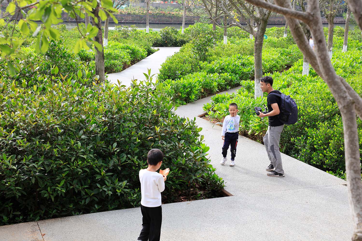 A man and two children on the pathways near the Meishe River wetland in Haikou, China