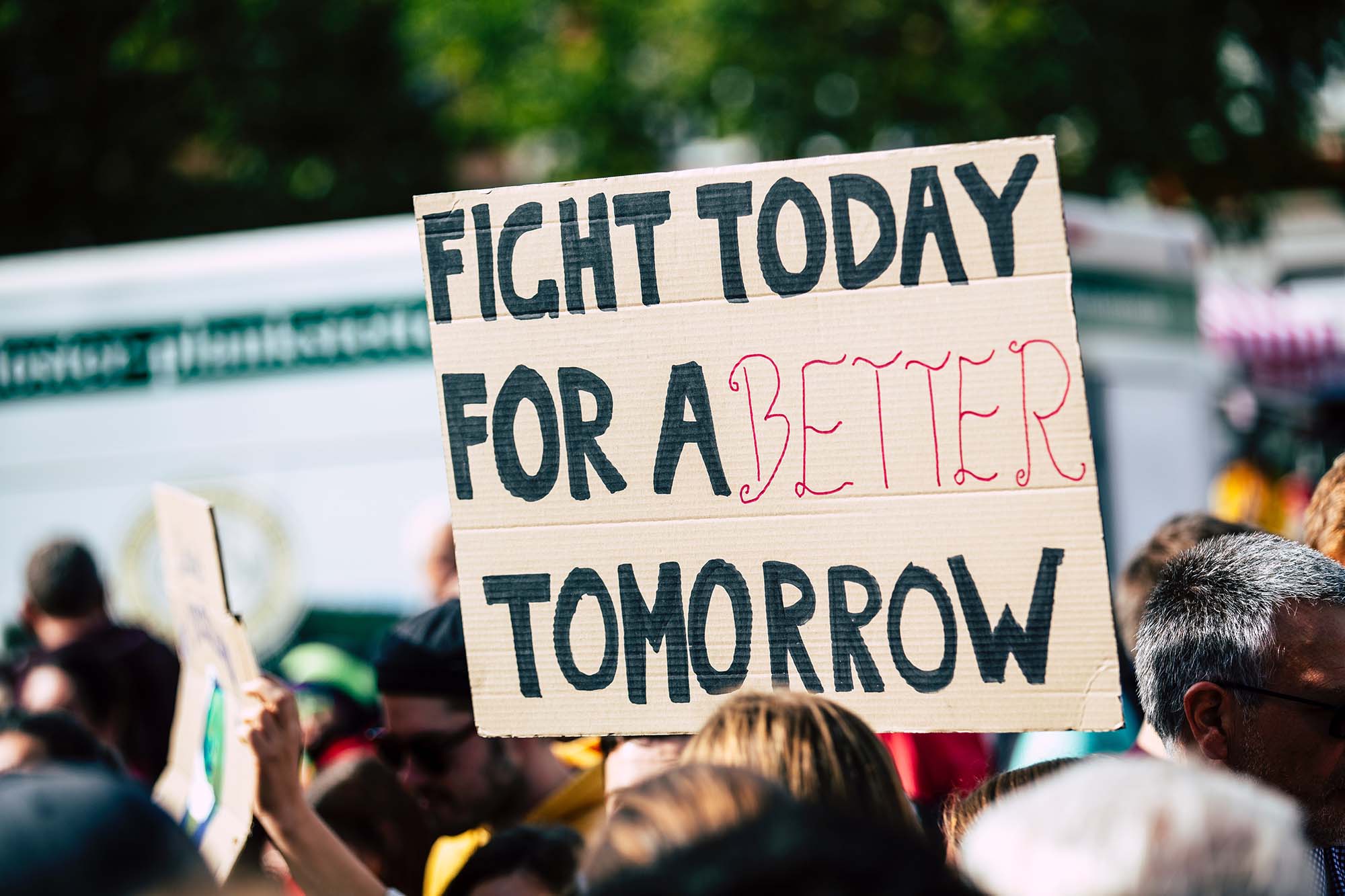 A protester holding a sign reading "fight today for a better tomorrow"
