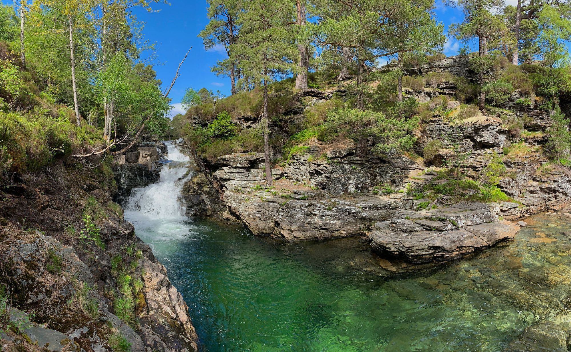 A waterfall and river running through tree-covered rocky land