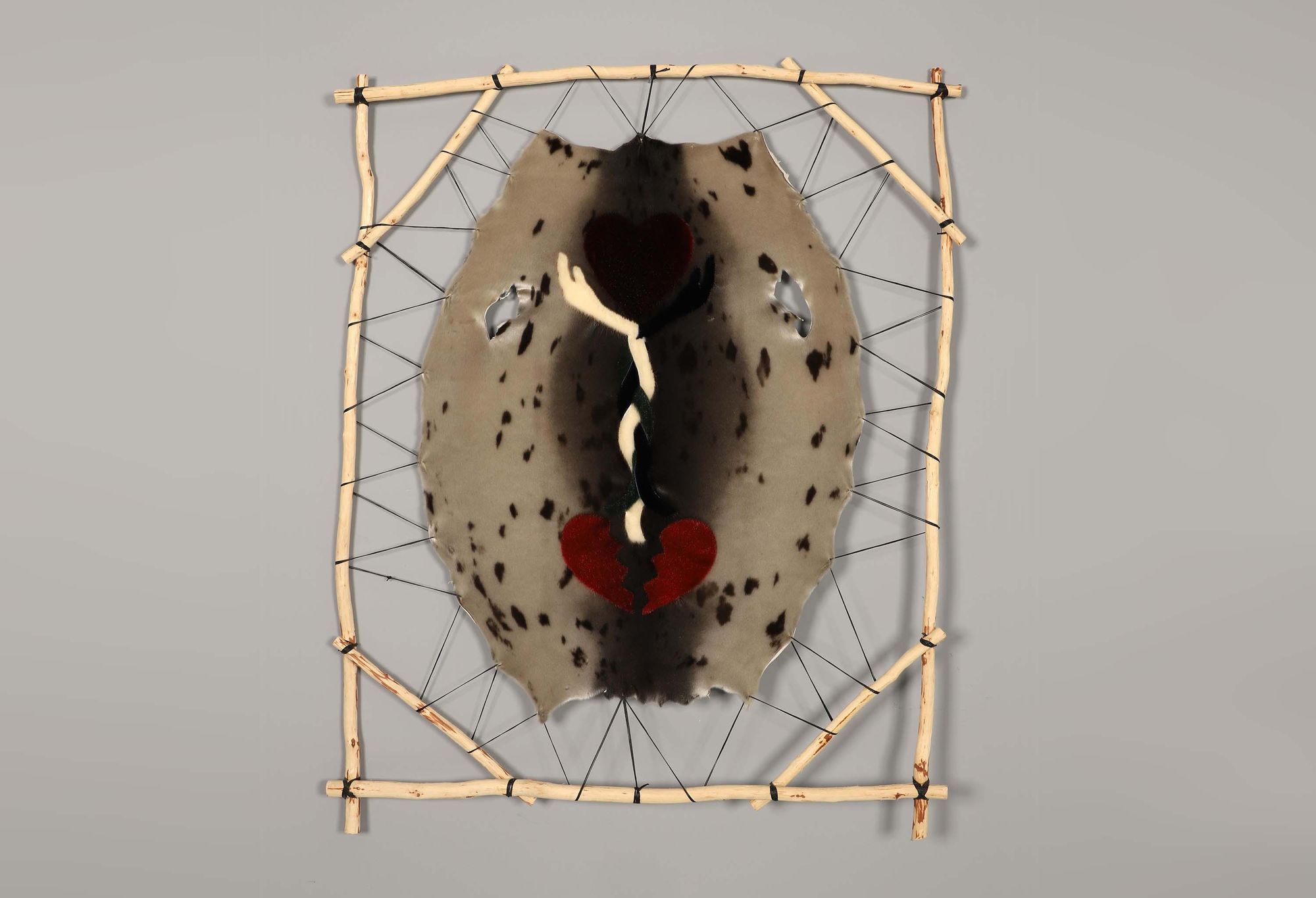 Art on sealskin depicting hearts and hands, stretched between a wooden frame
