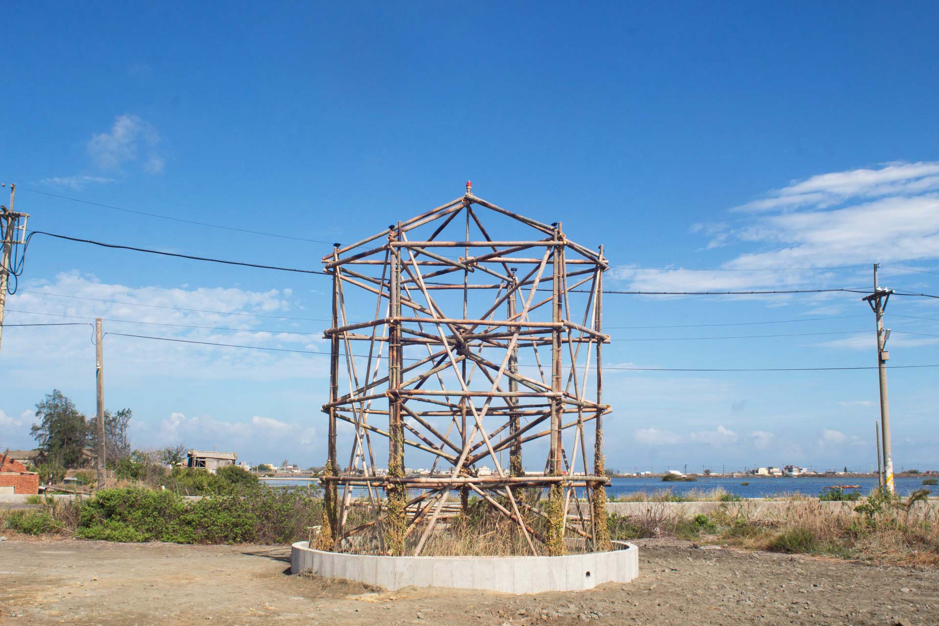 An art piece of interlocking pieces of bamboo in front of a blue sky and watery landscape