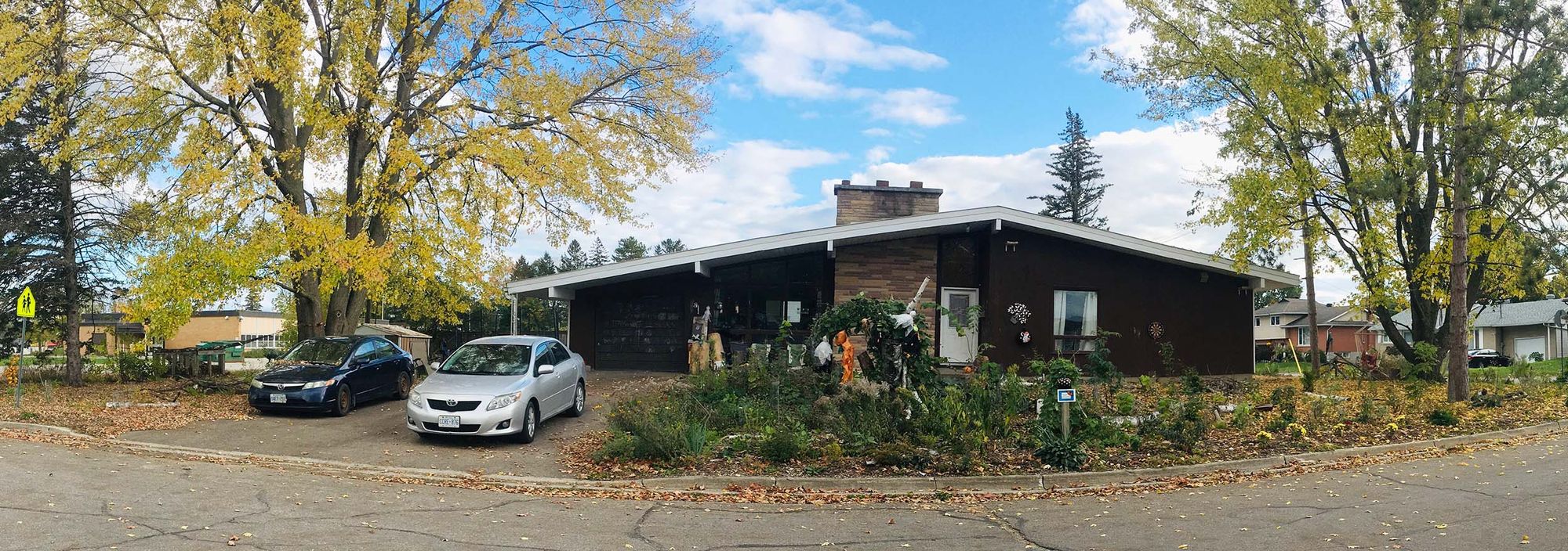 Wise panorama view of a house, garden and trees in fall