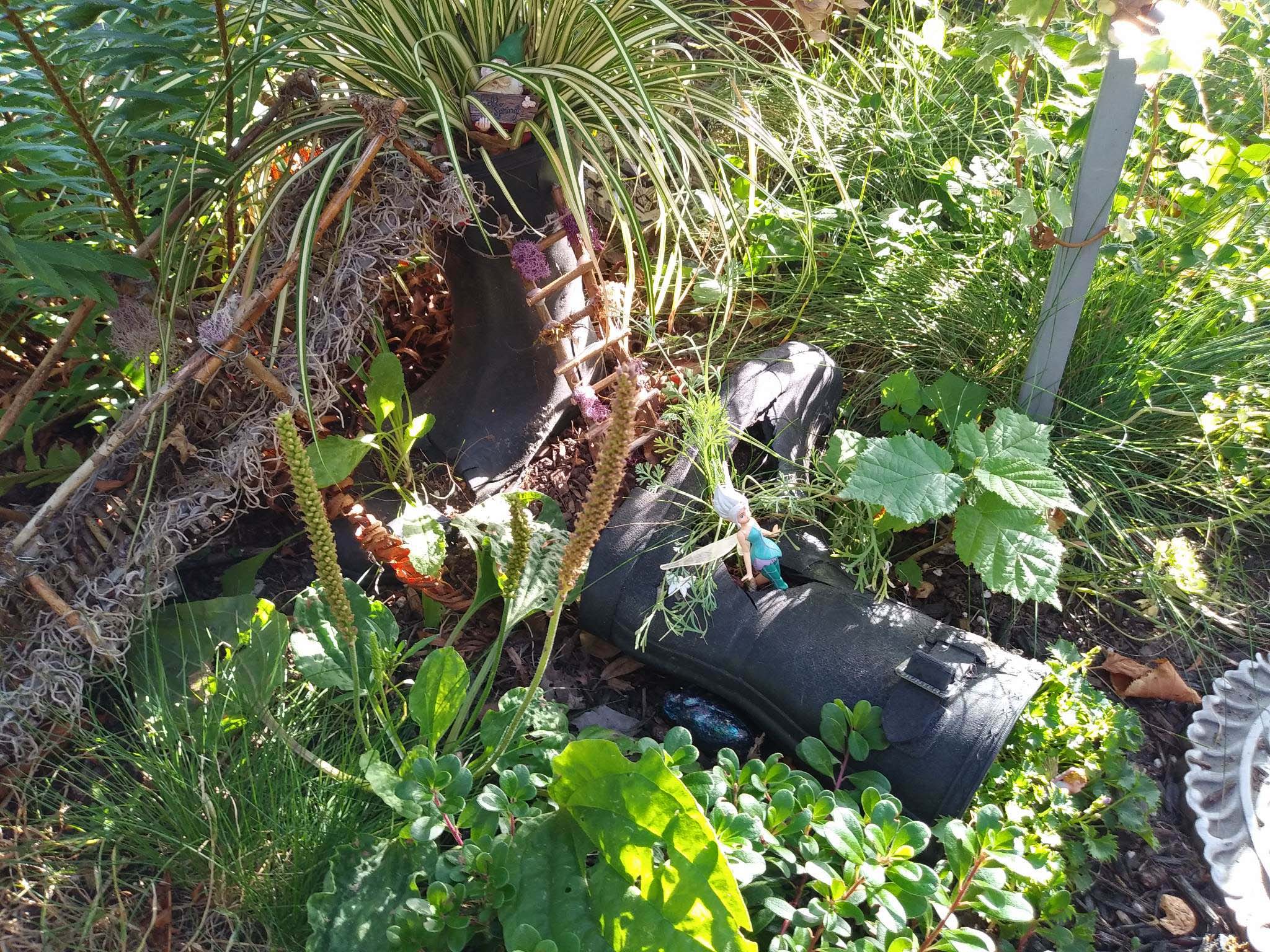 In a garden, a fairy house made from rubber boots