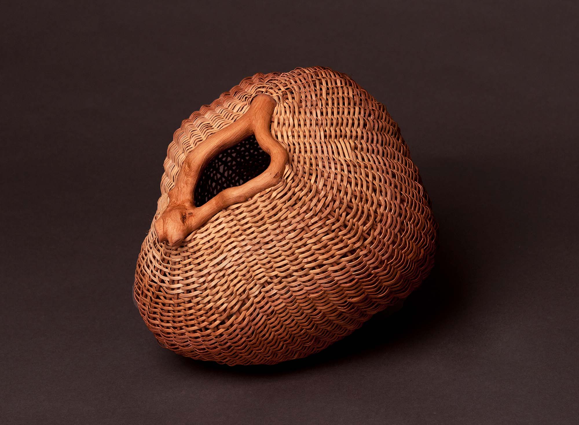 An organically shaped woven basket on a dark background