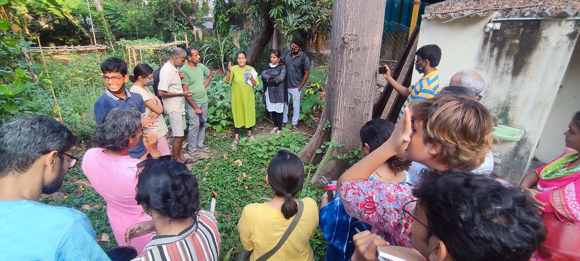 A group of people standing in a circle in a garden