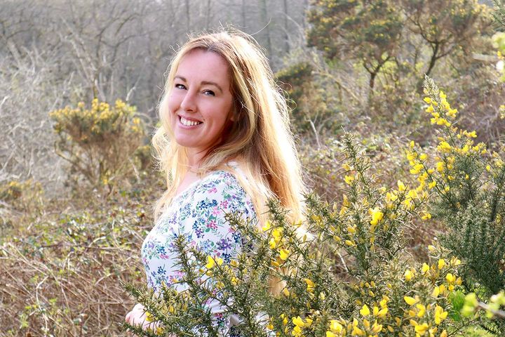 Victoria Hillsdon smiling amidst a landscape of yellow-flowering gorse.