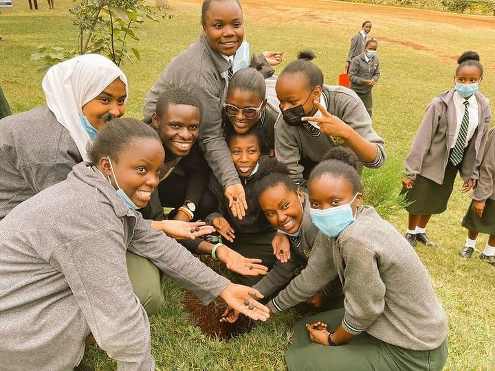 A group of students outdoors, gathered around their hands holding seeds.