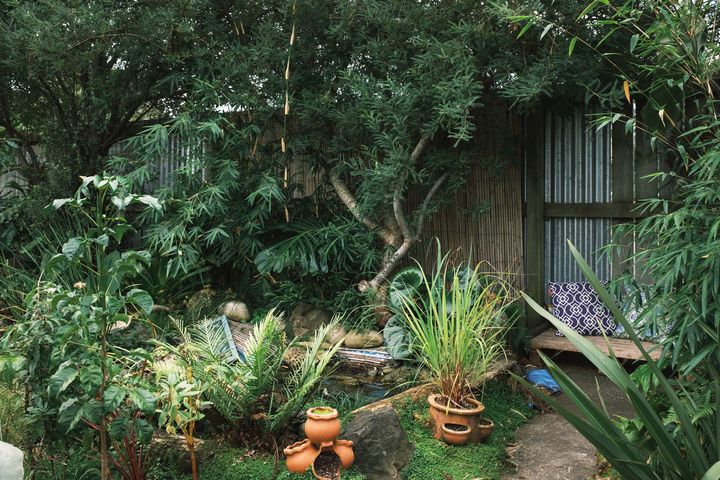 A lush green garden with a sitting area in the corner