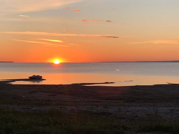 A scene with water and orange-tinted sky during sunrise or sunset
